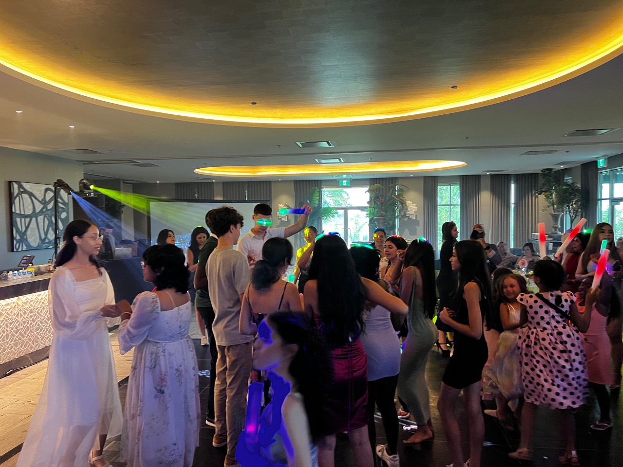 Invités dansant avec des bâtons lumineux pendant une Quinceañera
