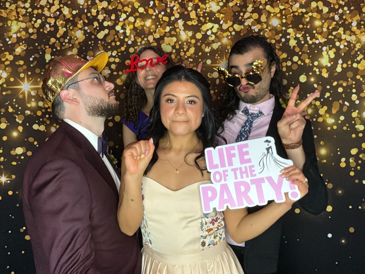 Mariés et amis devant le fond doré du photobooth numérique